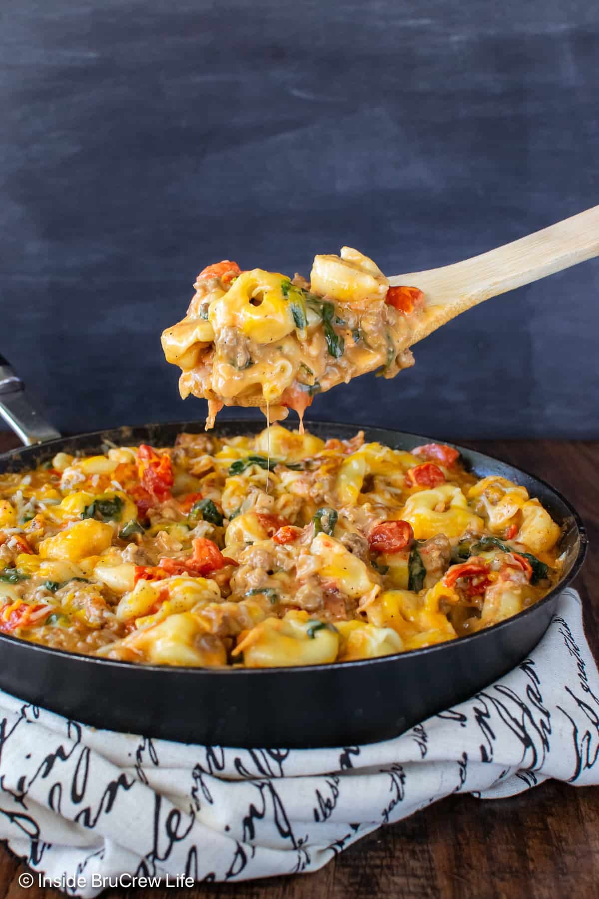 A skilled of cheeseburger tortellini with a spoon lifting some out.