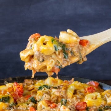 A skillet of cheeseburger tortellini with a spoon lifting some out.