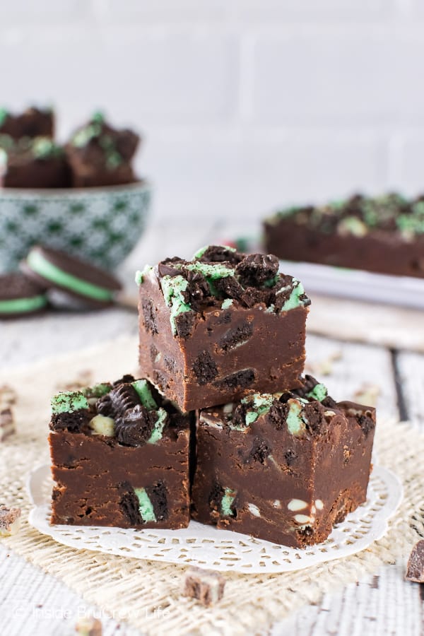 3 pieces of chocolate fudge loaded with green mint cookies and mint chips on a white doily.