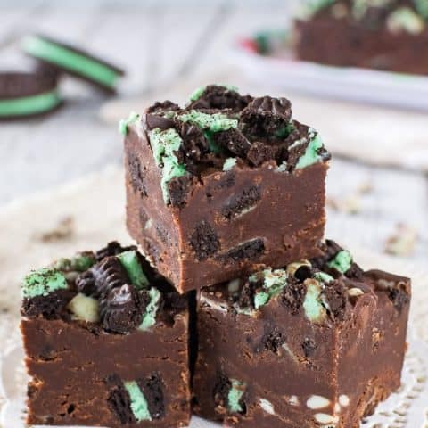 3 pieces of chocolate fudge loaded with green mint cookies and mint chips on a white doily.