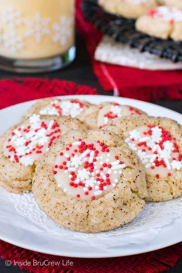 Eggnog Thumbprint cookies with white and red sprinkles on a white plate.