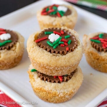 A white plate with peanut butter cup cookies topped with holiday sprinkles on it
