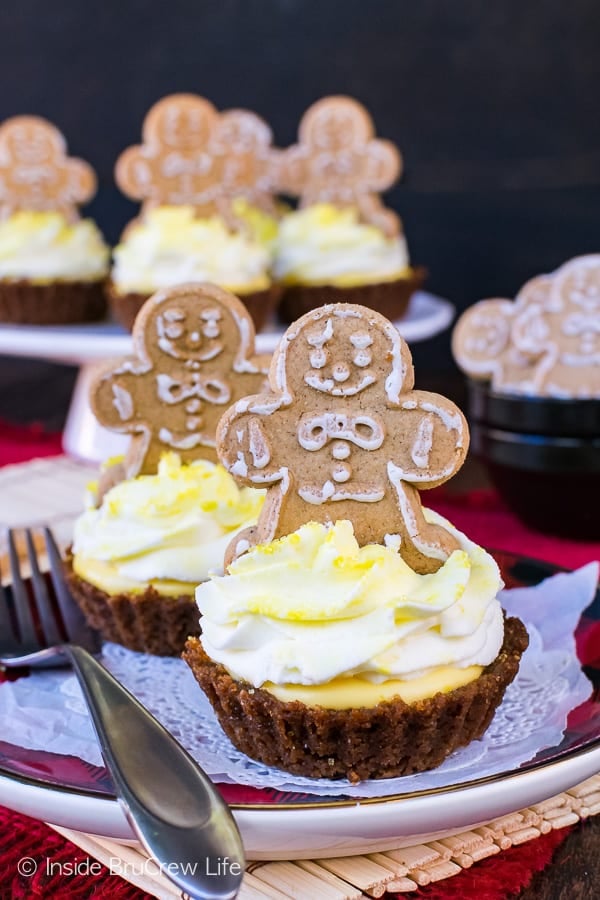 A gingerbread man sitting on top of a small Lemon Gingersnap Cheesecake Tart.