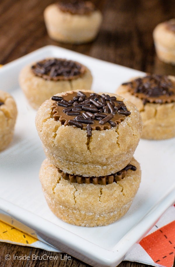 A white plate with five peanut butter cup cookies topped with brown sprinkles on it.