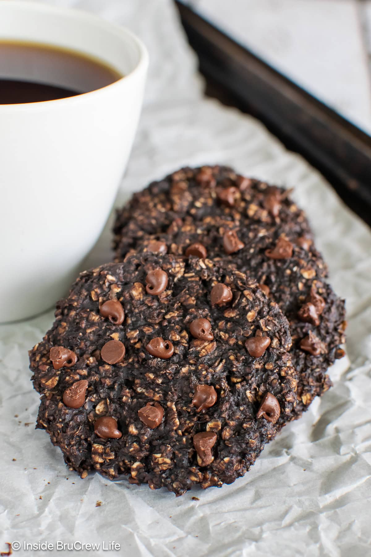 A couple of banana chocolate protein cookies on a lined pan.
