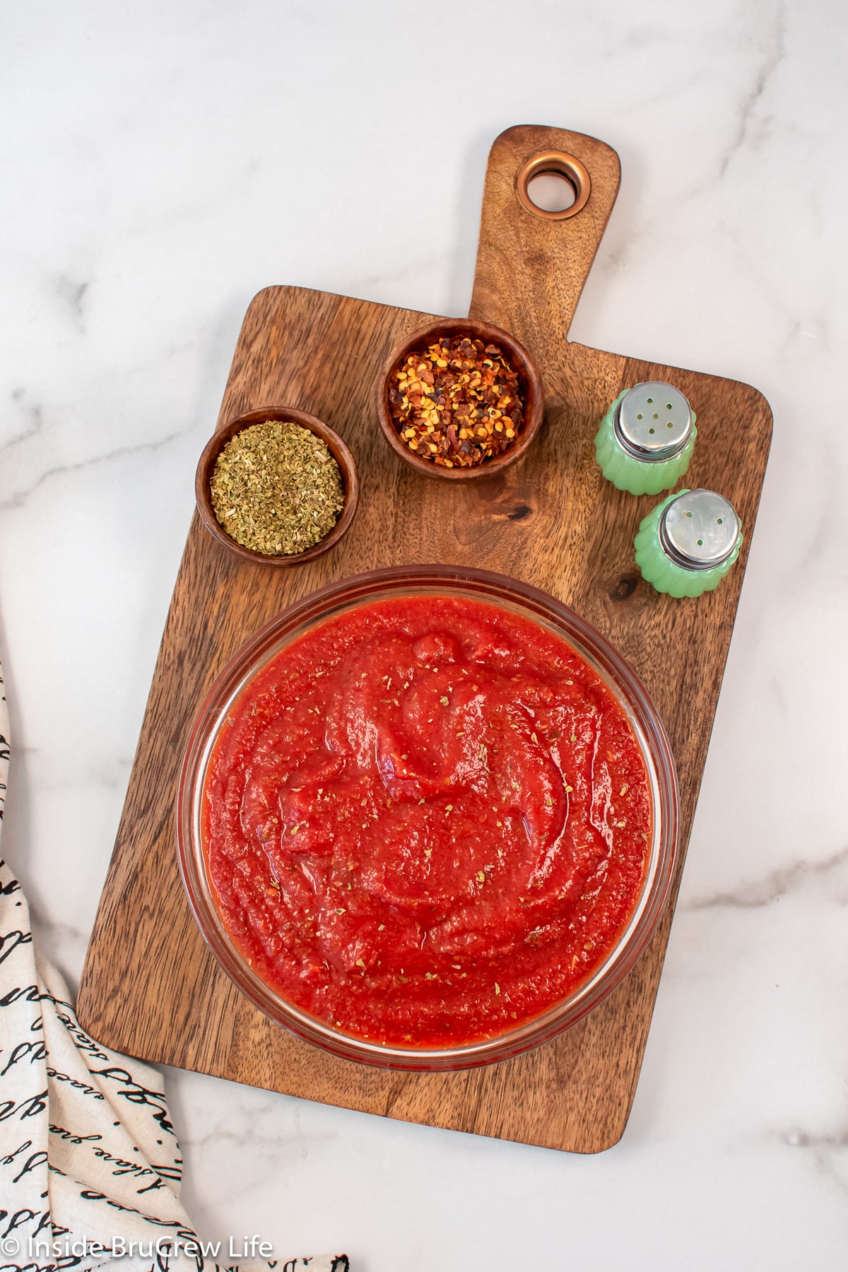 A glass bowl filled with pizza sauce.