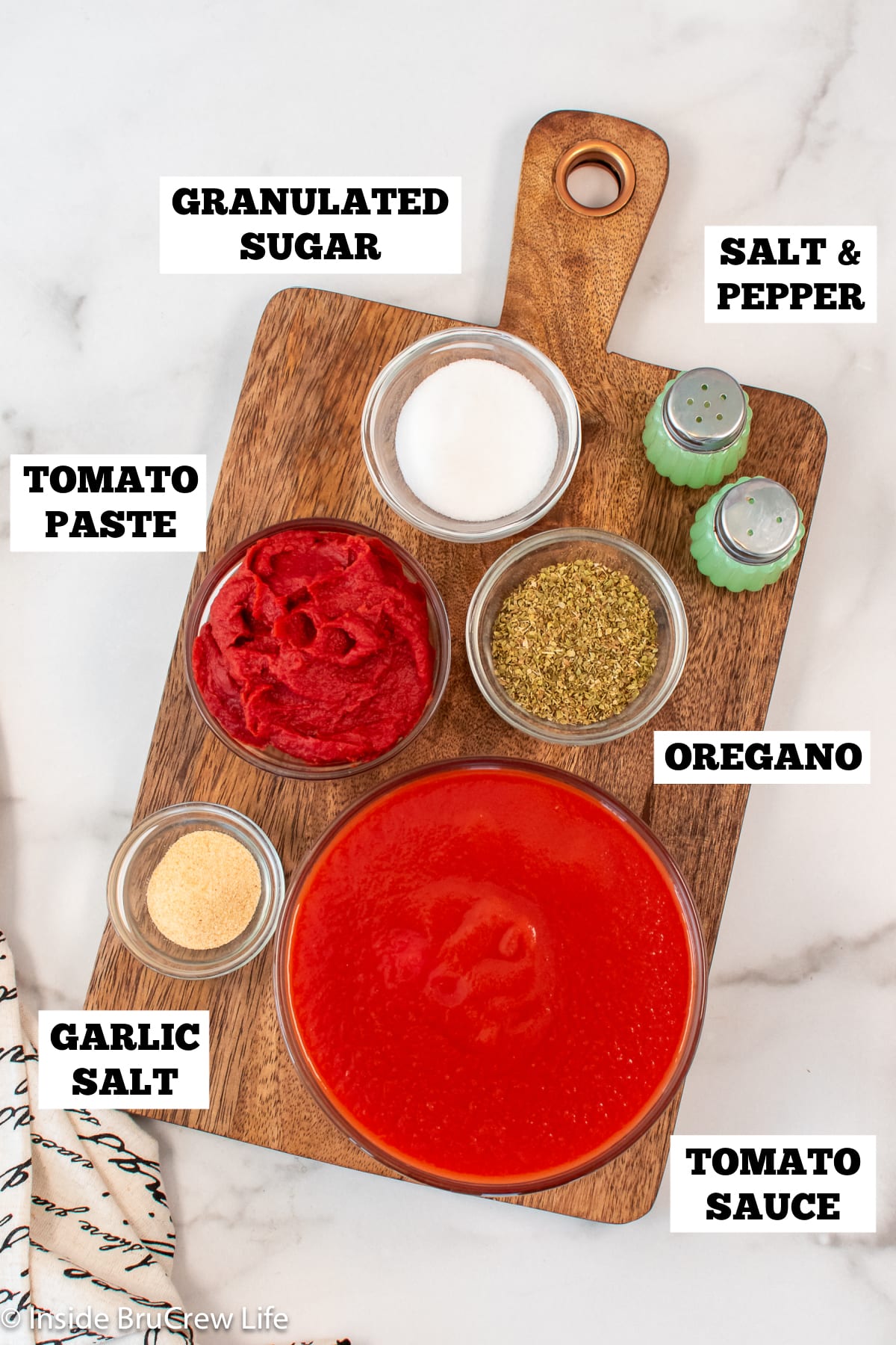 A white board with bowls of ingredients needed to make pizza sauce.