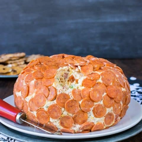 A cheese ball full of pizza toppings and covered in mini pepperonis.
