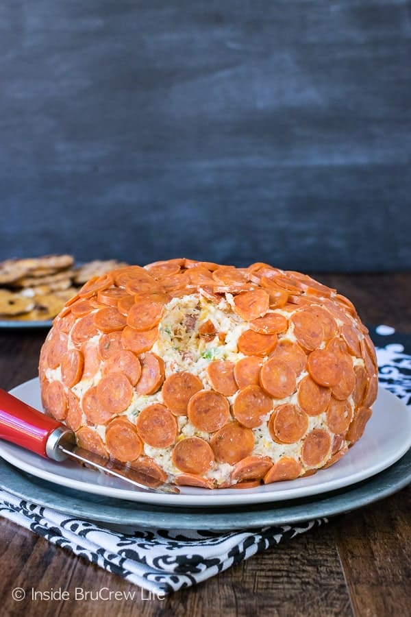 A cheese ball covered in mini pepperonis on a plate.