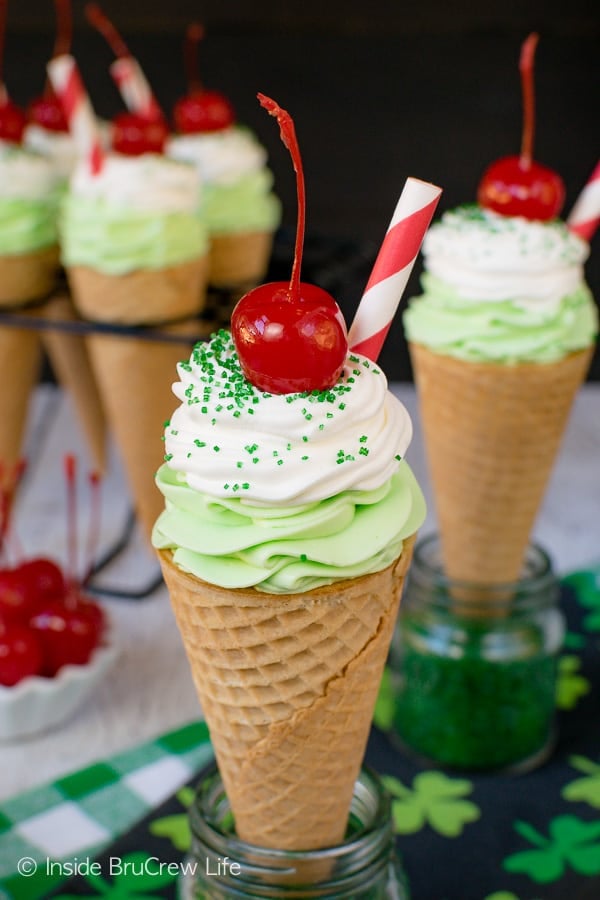  Ice cream cones filled with green shamrock cheesecake topped with a cherry.
