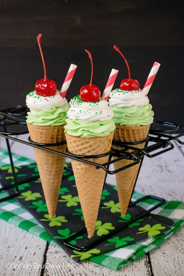 3 ice cream cones filled with green shamrock cheesecake topped with a cherry.