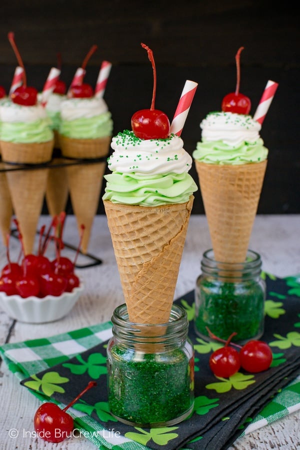 Ice cream cones filled with green shamrock cheesecake topped with a cherry.