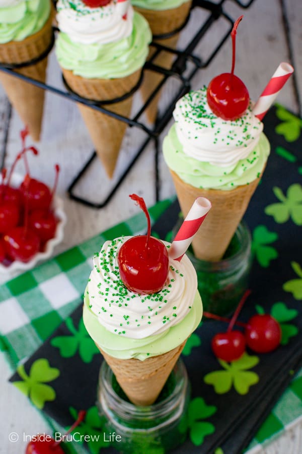 Ice cream cones filled with green shamrock cheesecake topped with a cherry.