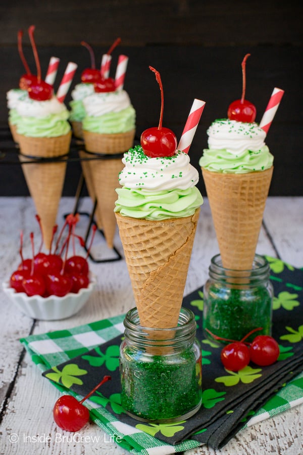 Ice cream cones filled with green shamrock cheesecake topped with a cherry.