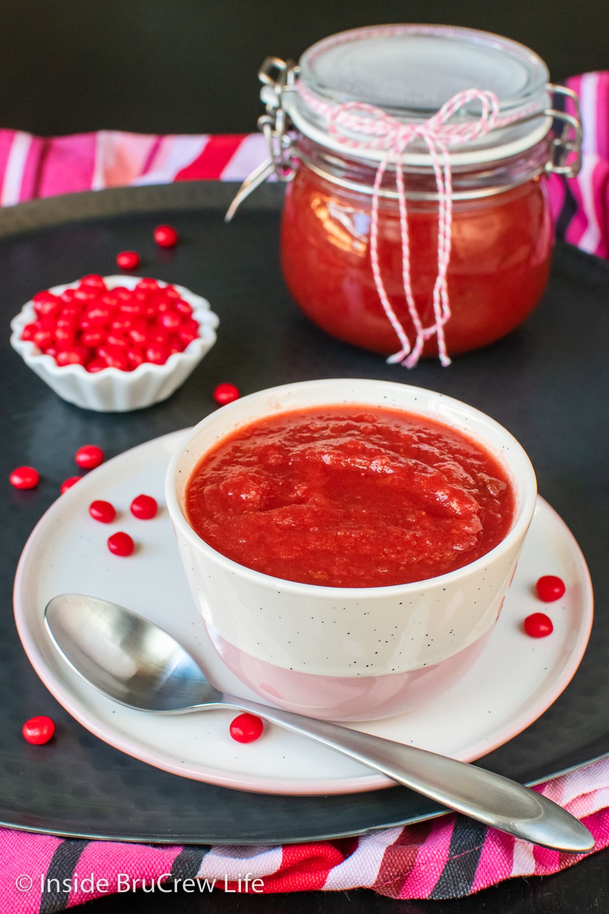 A white bowl filled with red strawberry applesauce.