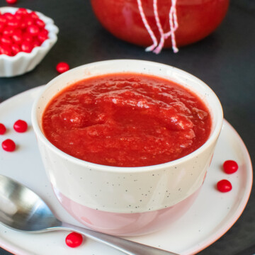 A white bowl filled with red strawberry applesauce.