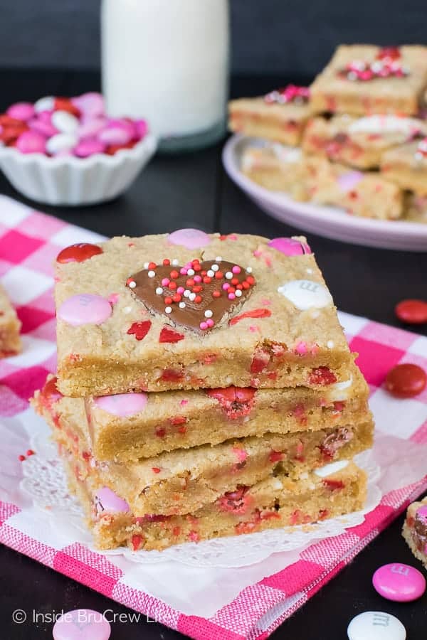 Stack of four Valentine Peanut Butter Heart Cookie Bars on a white doily and pink and white checkered towel