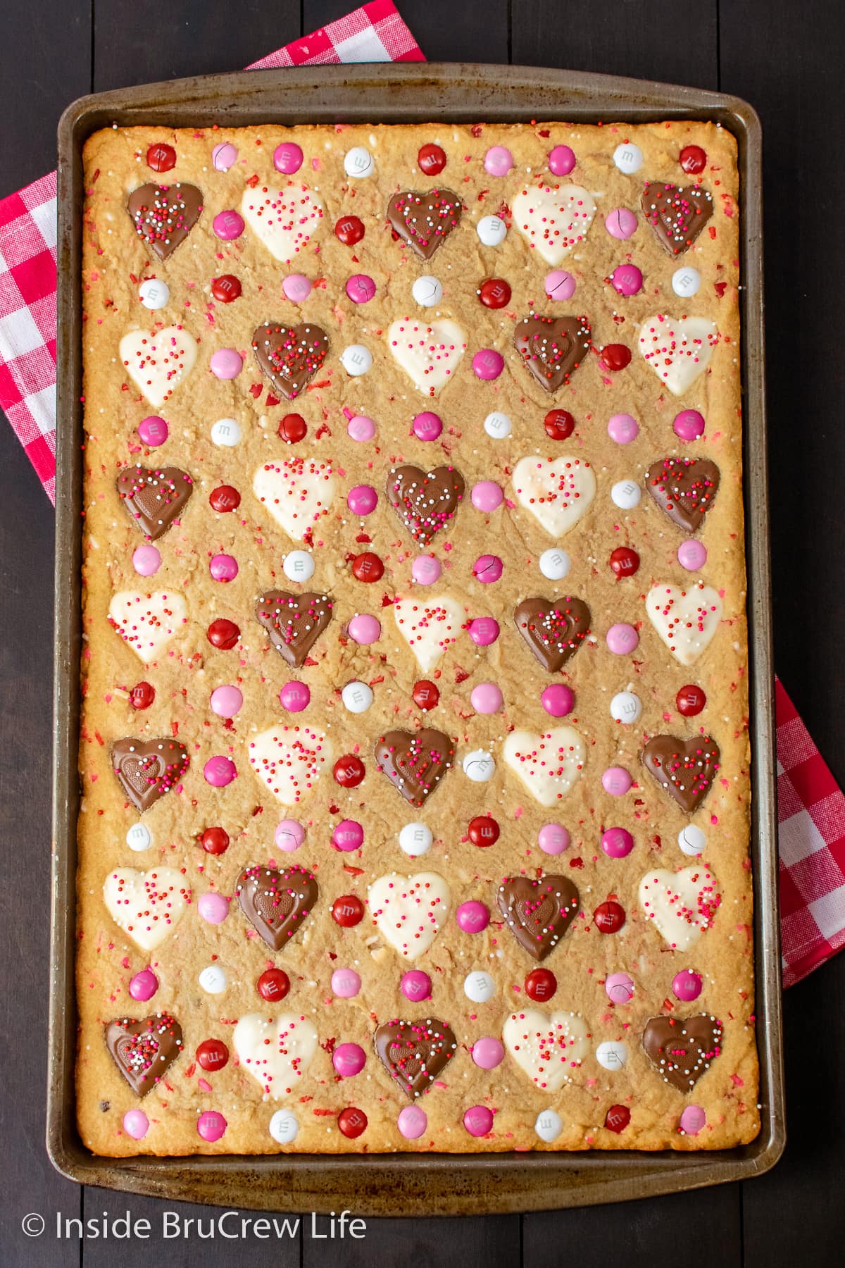 A sheet pan filled with peanut butter bars with Reese's hearts baked in them.