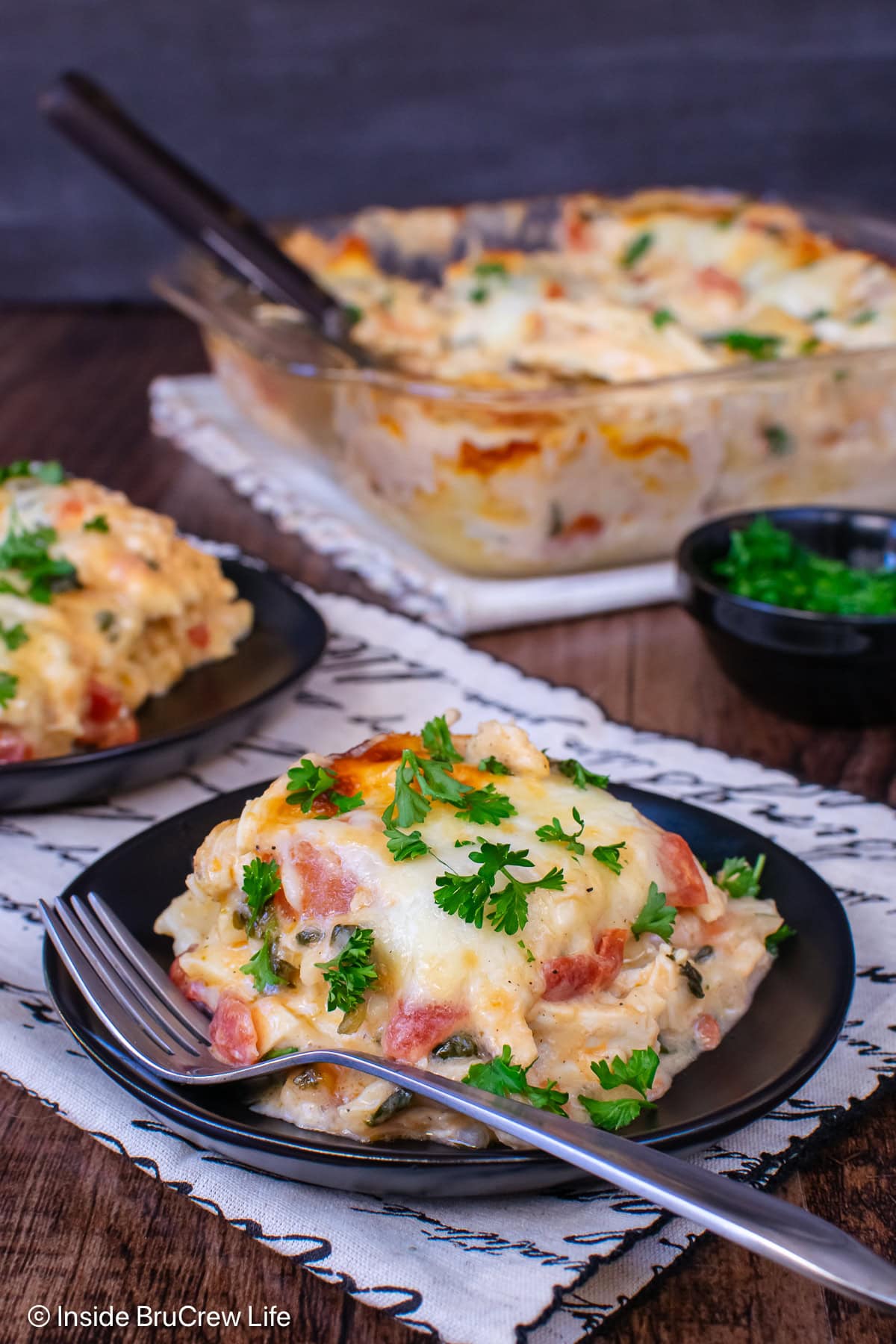 Two black plates of cheesy chicken bake on them.