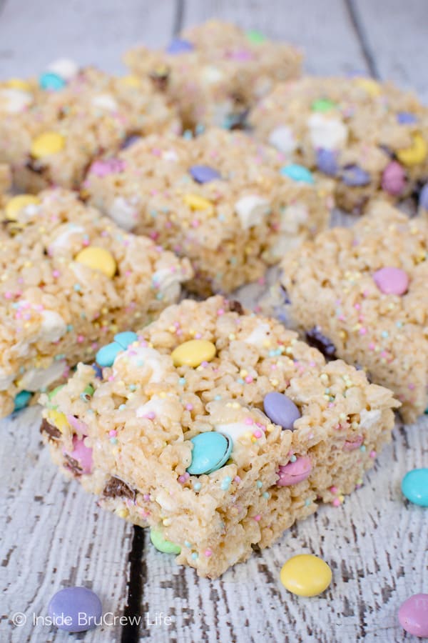 A white board with rice krispie treats with M&Ms and sprinkles laid out on it