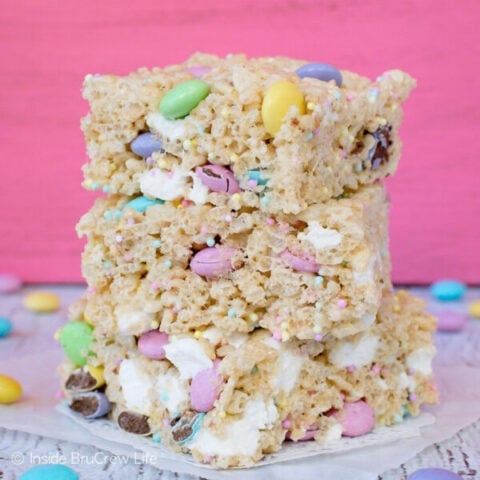 A stack of three Easter rice krispies treats stacked on top of each other with a pink background