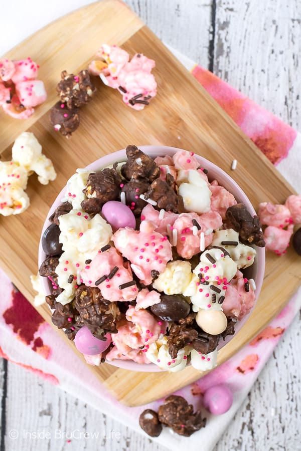 Neapolitan Popcorn - this easy popcorn is coated in chocolate, strawberry, and vanilla chocolate and has a bag of candy mixed in. Easy recipe to make and snack on during movie night. #popcorn #chocolate #strawberry #nobake #snackmix #neapolitan 