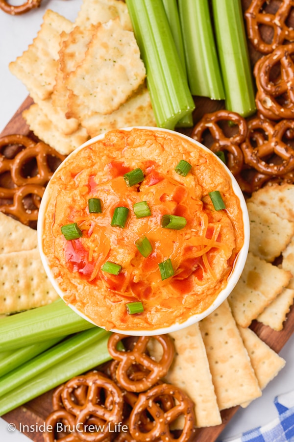 Overhead picture of a white bowl with cheese dip and snacks around it.