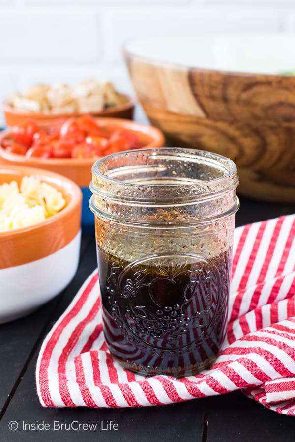 Un asciugamano a righe bianche e rosse con un barattolo trasparente riempito con una vinaigrette balsamica fatta in casa