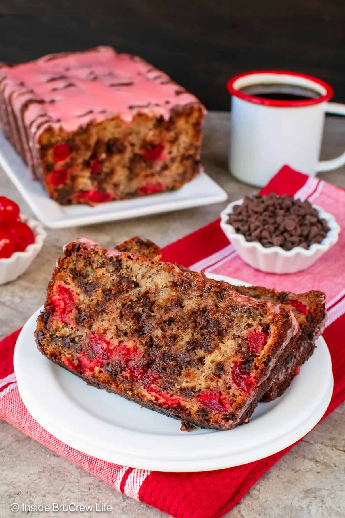 Two slices of chocolate cherry banana bread on a white plate.