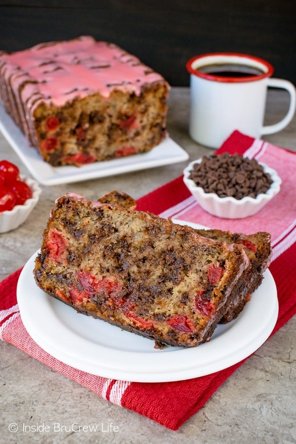 Two slices of banana bread with cherries on a white plate.