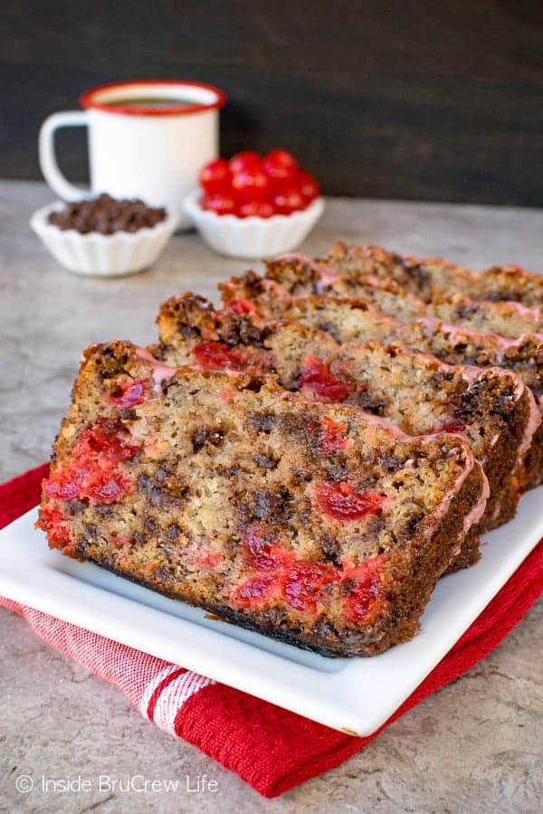 Slices of banana bread with cherries and chocolate chips on a white plate.