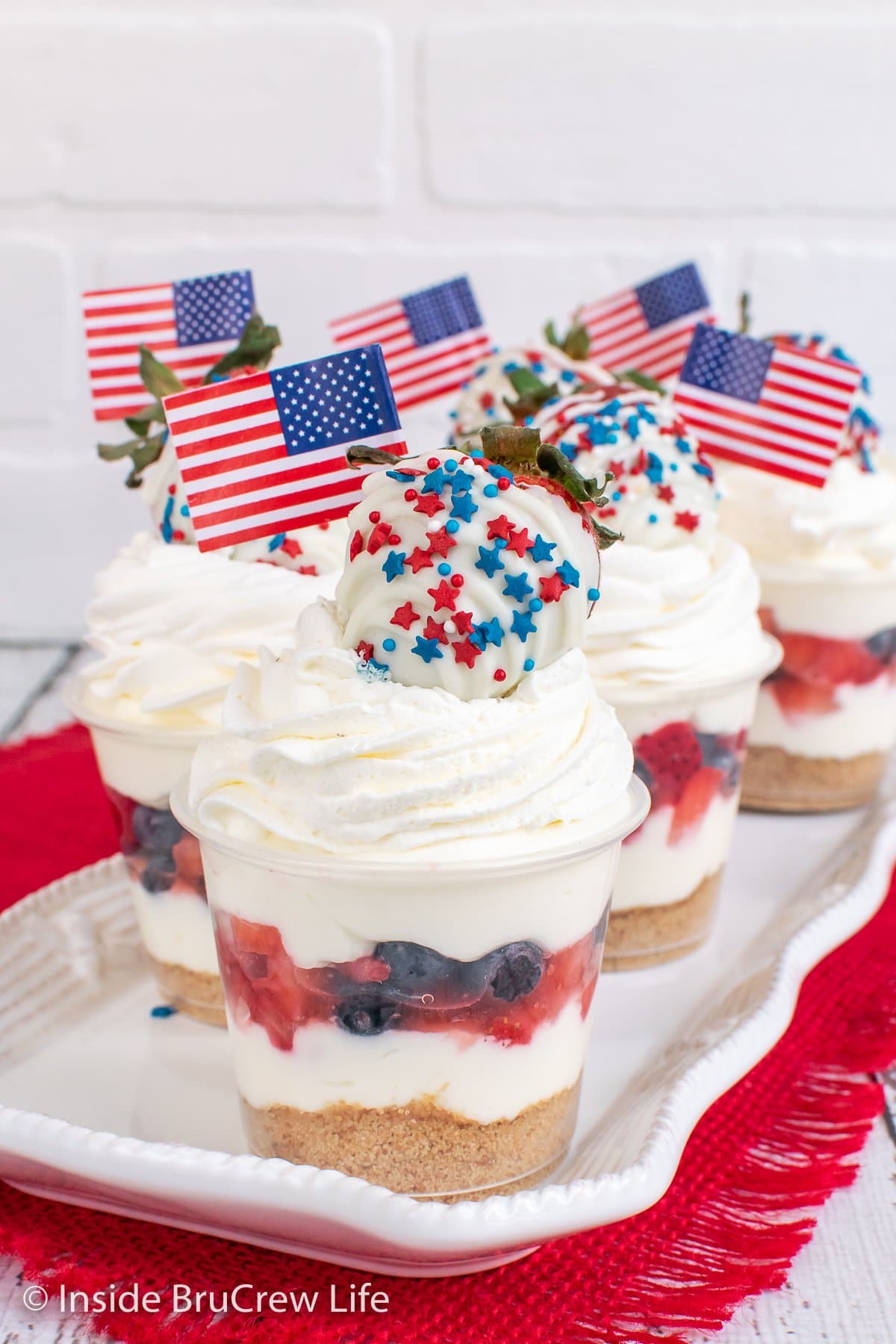 A tray of cheesecake cups with a layer of red and blue fruit in them.