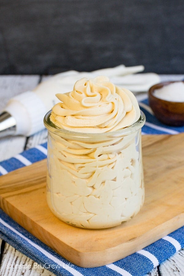 A board with a clear jar on it filled with salted caramel frosting. 