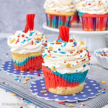 Two red white and blue cupcakes with candy fuse on top.