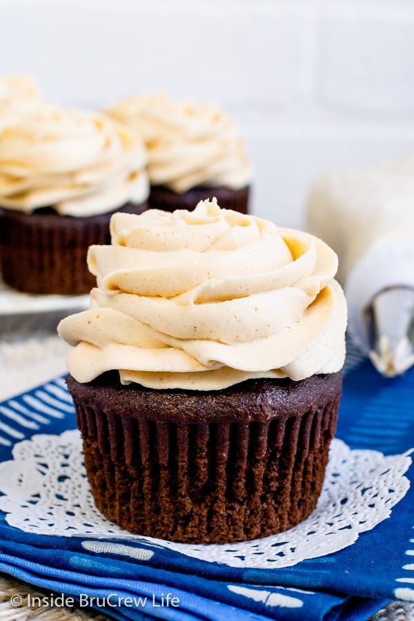 A chocolate cupcake with a swirl of peanut butter frosting on it and more cupcakes behind it.