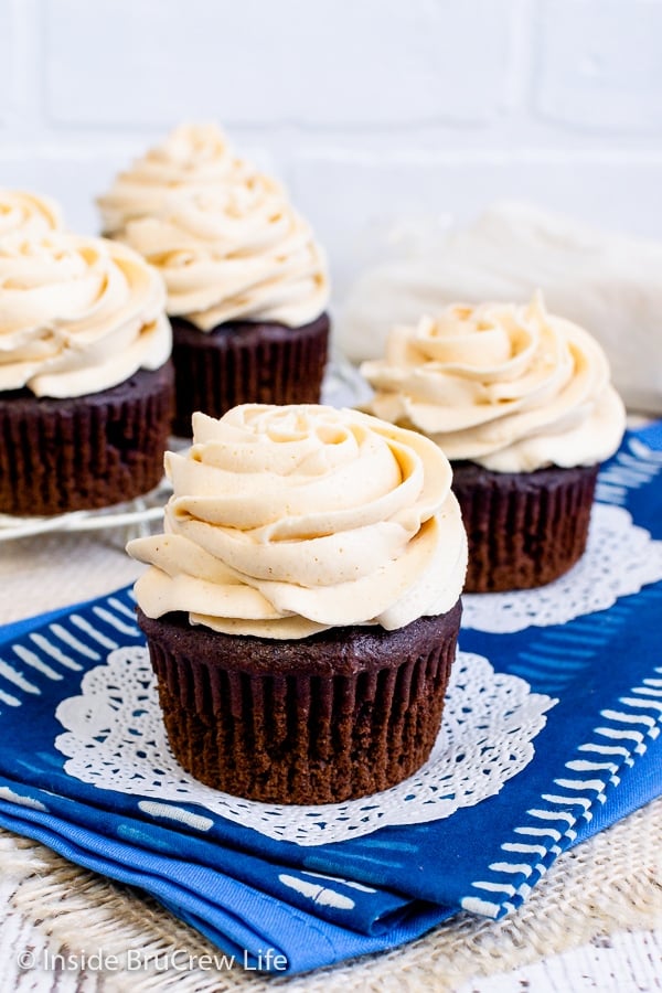 Two chocolate cupcakes with peanut butter frosting swirls on a blue towel.