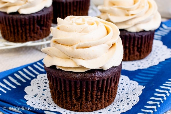 Two chocolate cupcakes on a blue towel with a swirl of peanut butter icing on them.