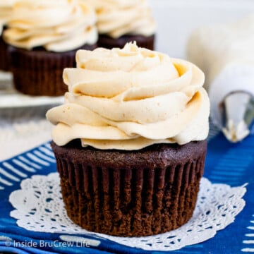 A chocolate cupcake on a blue towel with a honey peanut butter frosting swirl on top.