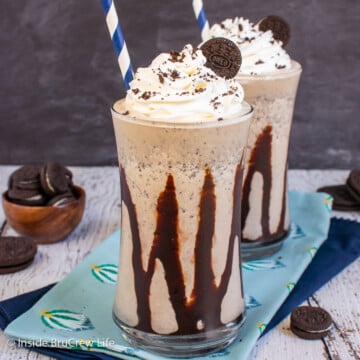 Two clear cups drizzled with chocolate and filled with a cookie shake.