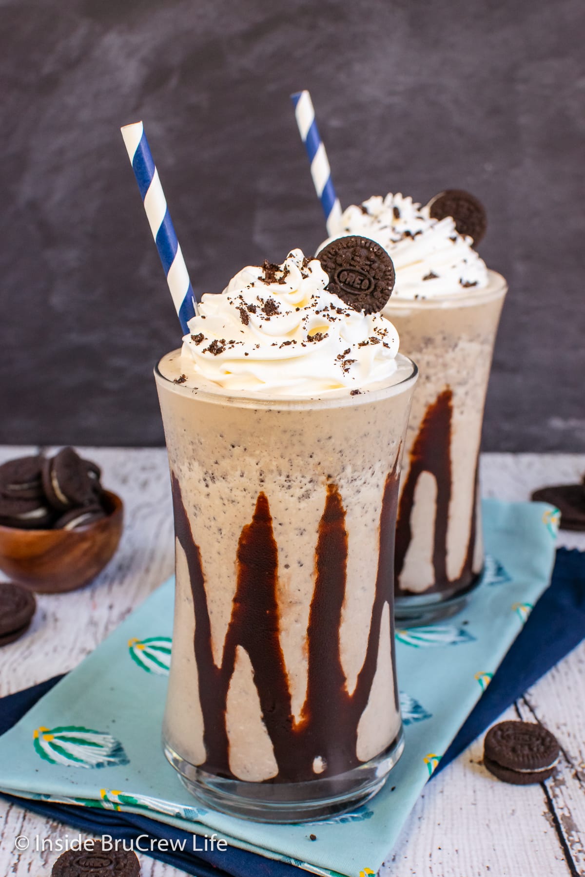 A cookie shake in a clear cup with chocolate drizzles.