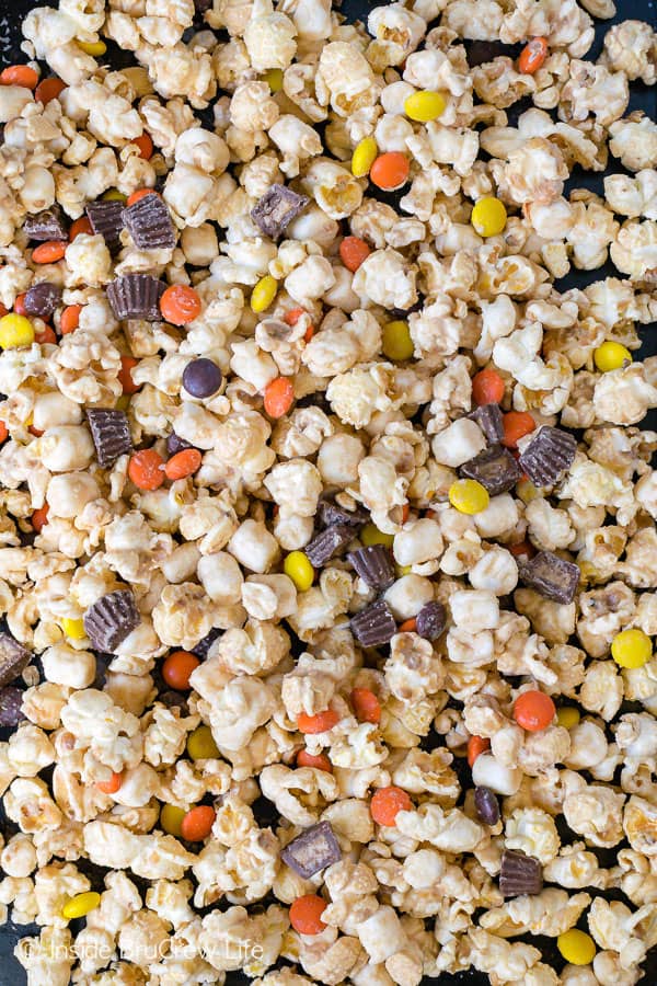Salted Caramel Reese's Popcorn - this caramel coated snack mix is loaded with peanut butter cups, Reese's pieces, and sea salt. Make this recipe for your next movie night! #popcorn #saltedcaramel #peanutbuttercups #reesespieces #snackmix #nobake #sweetandsalty