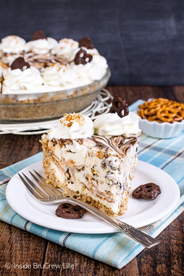 A slice of chubby hubby ice cream pie on a white plate and blue towel with a fork beside it.