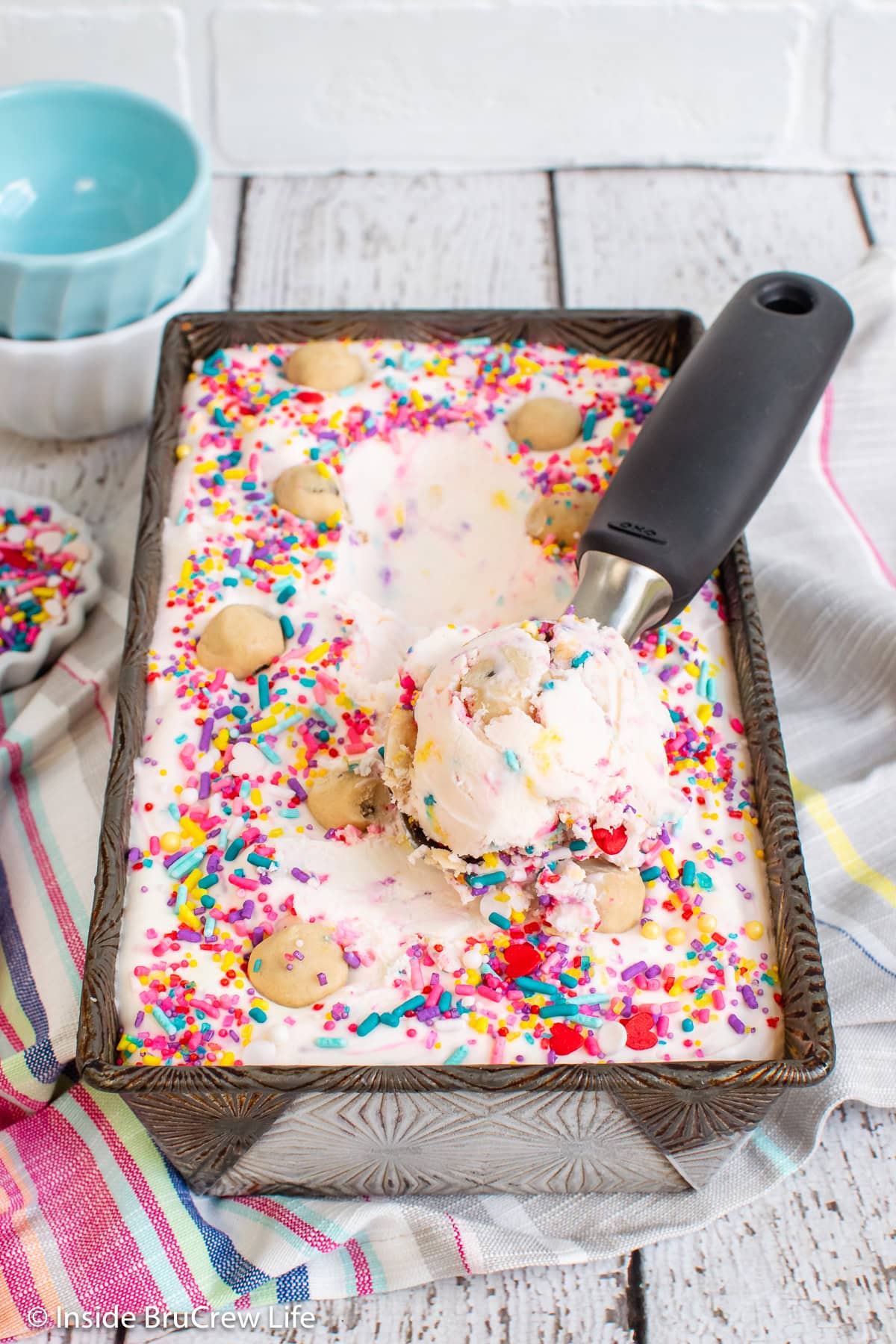 A pan filled with confetti ice cream and a scoop in it.