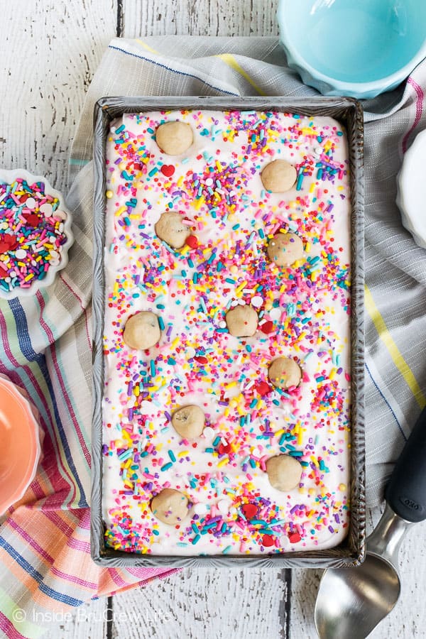 A metal loaf pan filled with frozen ice cream topped with sprinkles and cookie dough chunks.