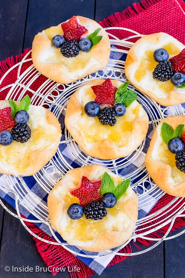 Overhead picture of a white wire rack with lemon cheese danishes with lemon curd and fruit on it.