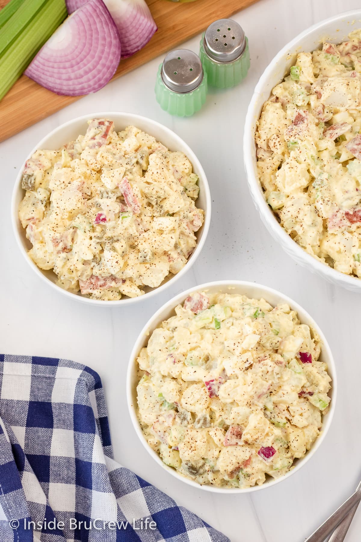 Overhead picture of three white bowls full of potato salad.