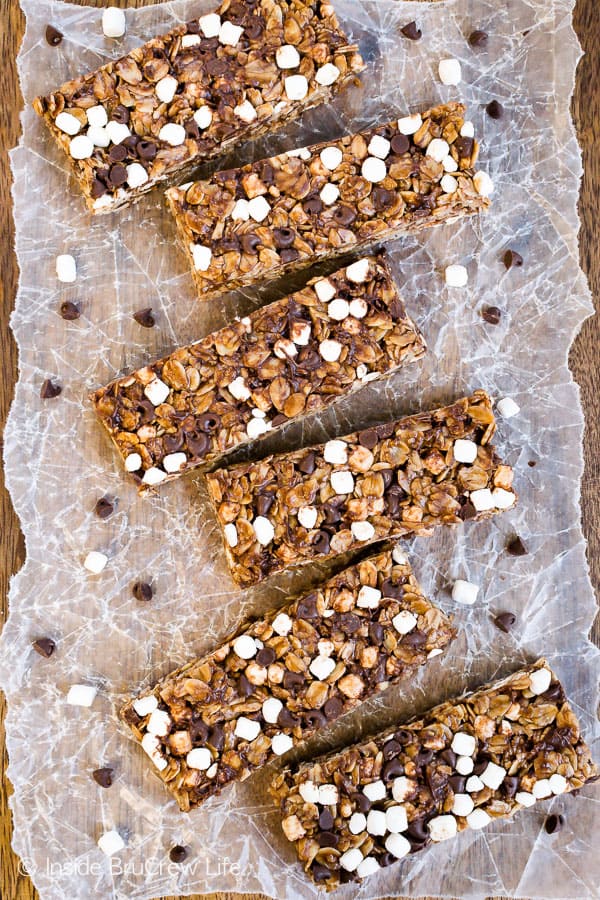 A row of no bake nutella s'mores granola bars lined up on a parchment paper lined cutting board