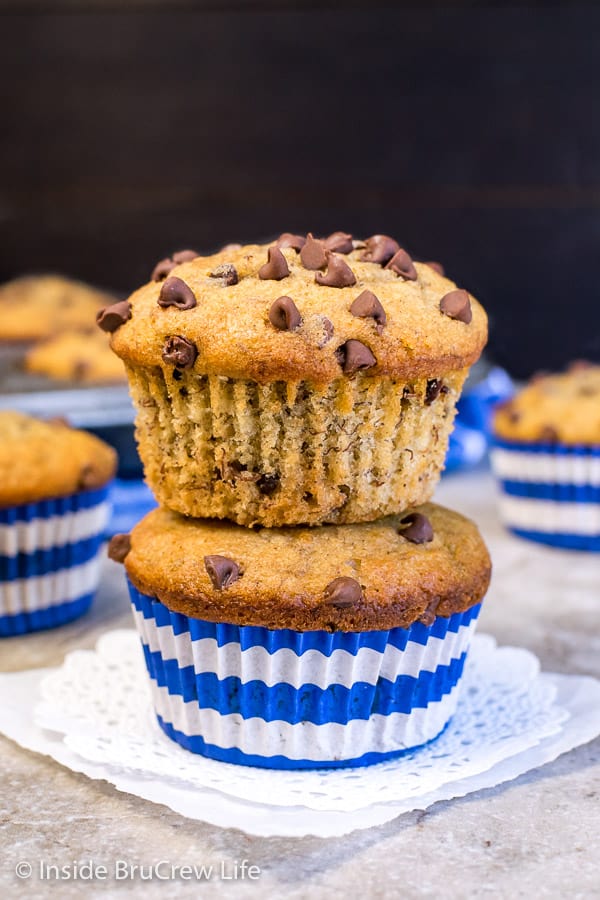 Two peanut butter chocolate chip banana muffins stacked on top of each other on a white doily.