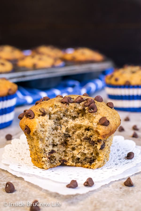 A close up picture of peanut butter  muffin on a white doily with a bite taken out of it.