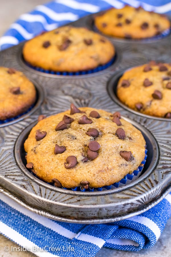 A close up picture of a peanut butter chocolate chip banana muffin in a silver muffin tin.